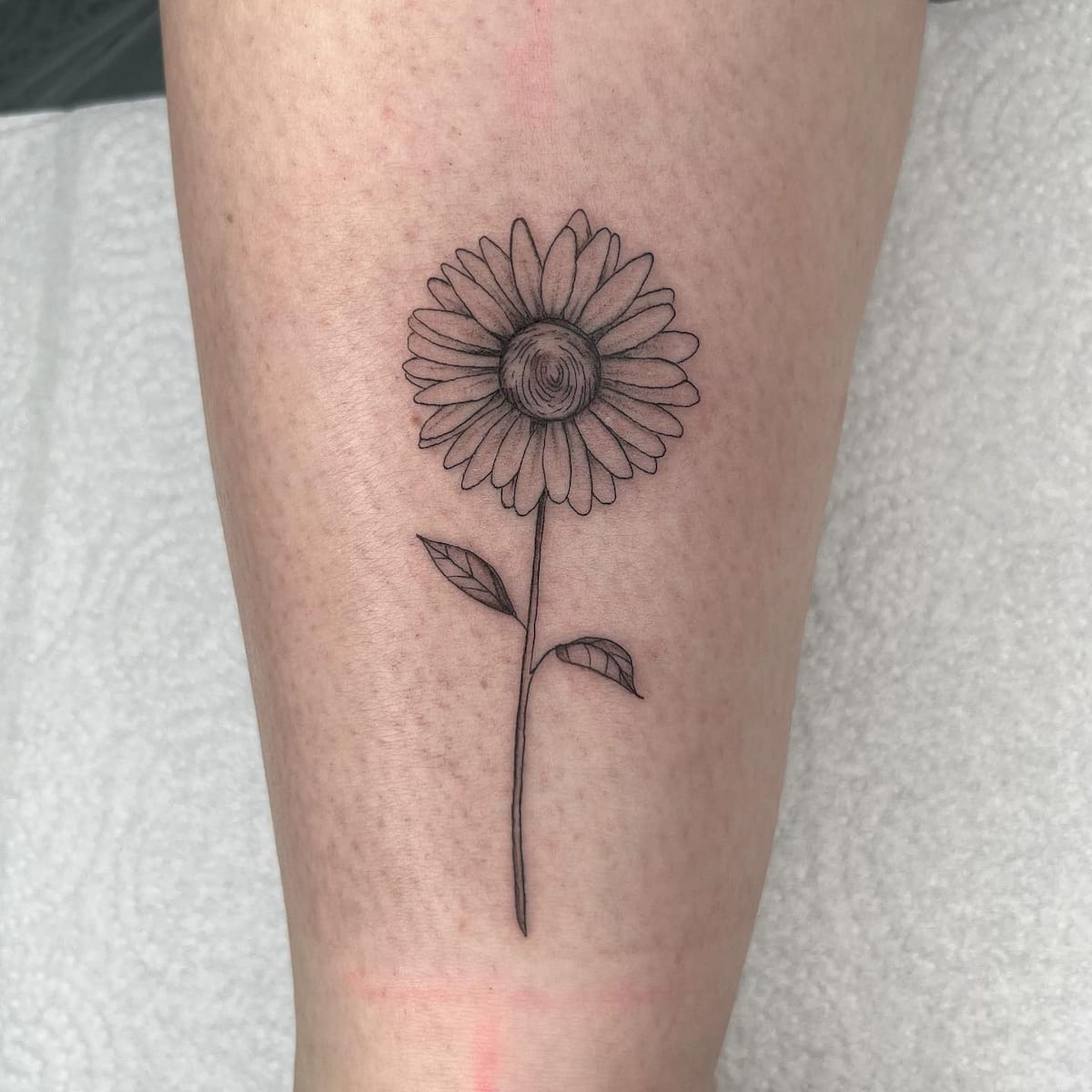 Minimalist daisy flower tattoo on the hand.