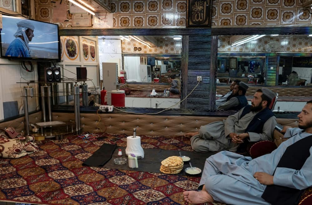 Afghan men watch television in a Kabul restaurant, a banned activity during the Taliban's first regime