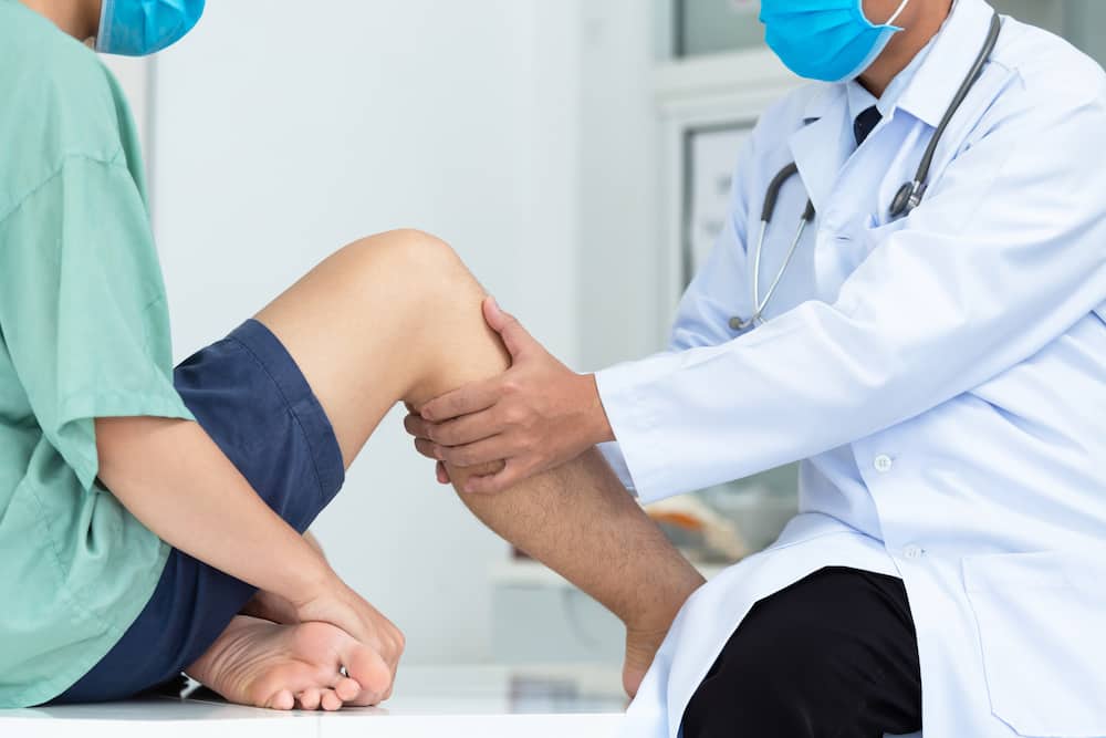 Orthopaedic examining a patient's knee
