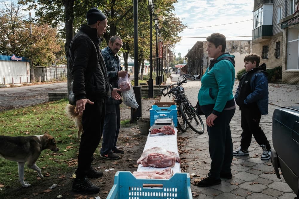 People buy meat from vendors in the recently retaken town of Lyman in Donetsk region