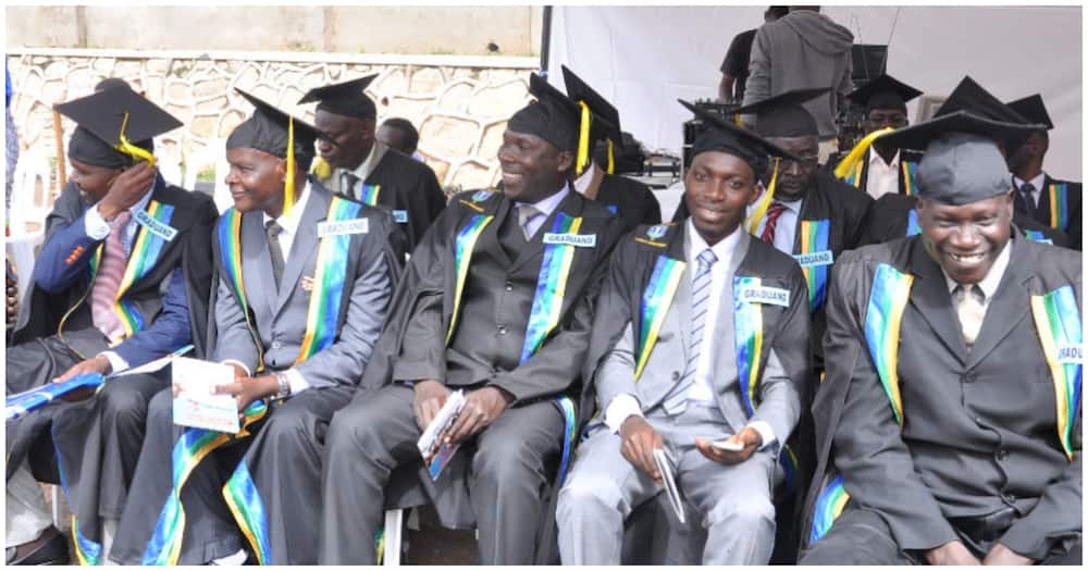 Men dressed in graduation gowns laughing while seated.