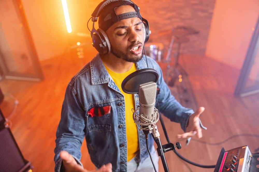 Black male rapper recording a music album in a beautiful studio.