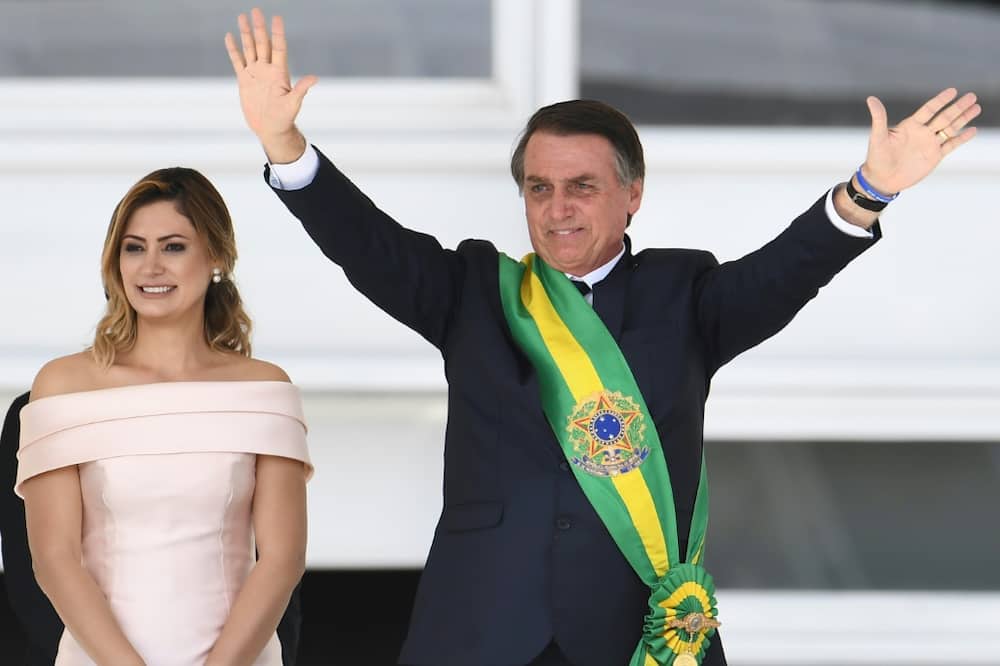 In January 2019, Brazil's new president Jair Bolsonaro (R) waves to supporters next to his wife Michelle after receiveing the presidential sash from outgoing president Michel Temer at the presidential palace in Brasilia