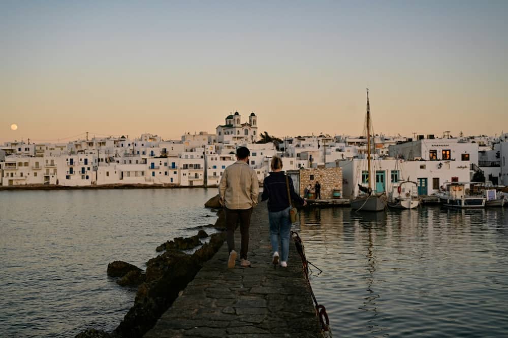 Tourists take a sunset stroll in the fishing village of Naoussa on the Greek island of Paros