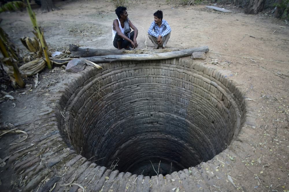 Villagers sit near a dried up well in Agrotha