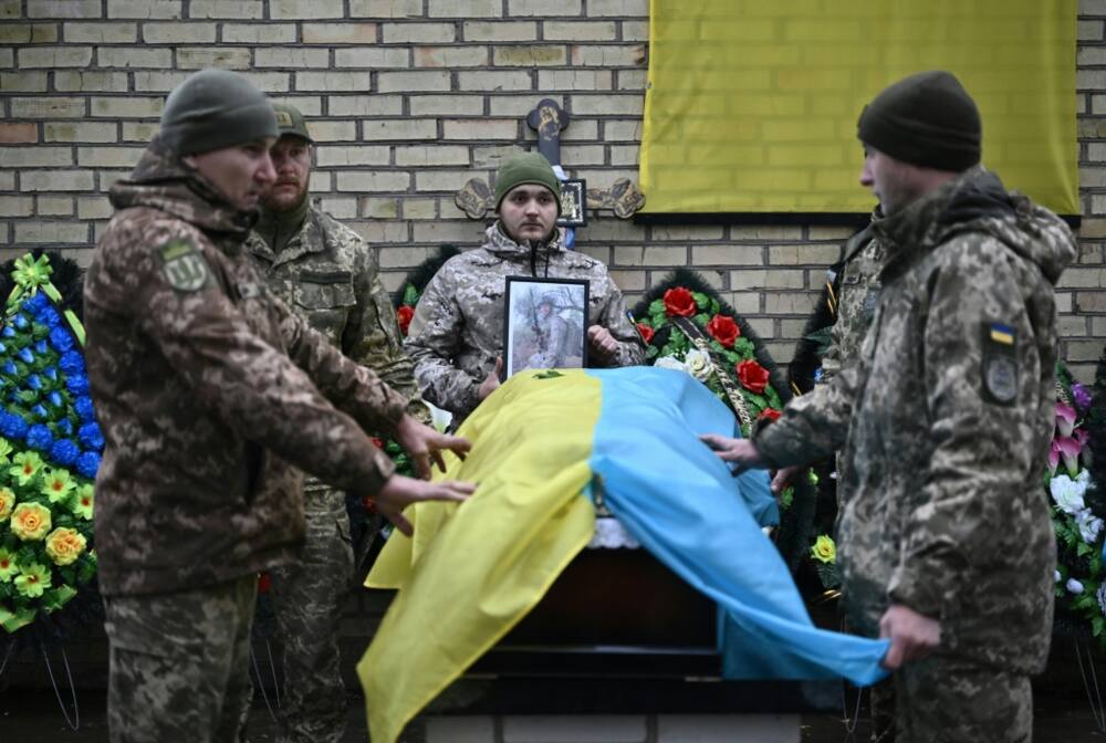 Ukraine military hold Ukrainian flag over a coffin during a funeral ceremony in Bucha near Kyiv