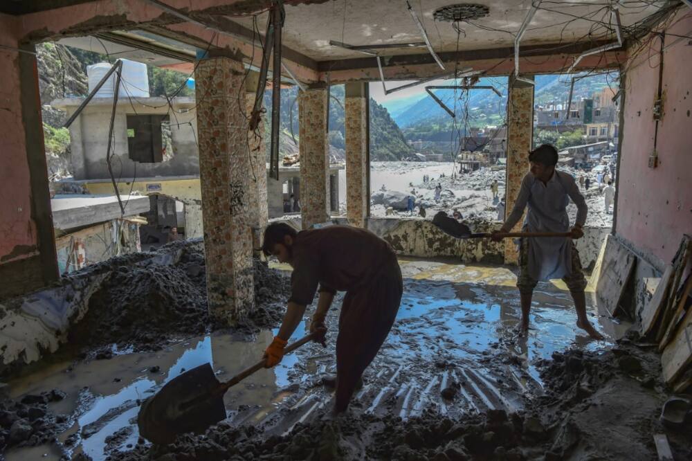 Workers clear sludge from a hotel badly damaged by flash floods of the Swat River near Bahrain in Khyber Pakhtunkhwa province