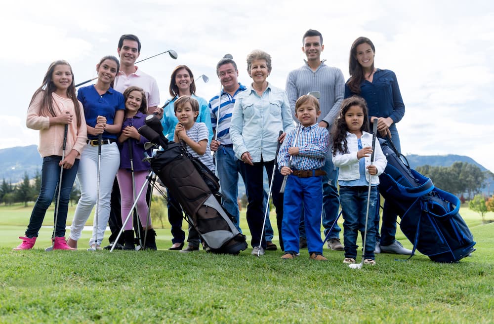 Multi-generation group of people playing golf and looking very happy