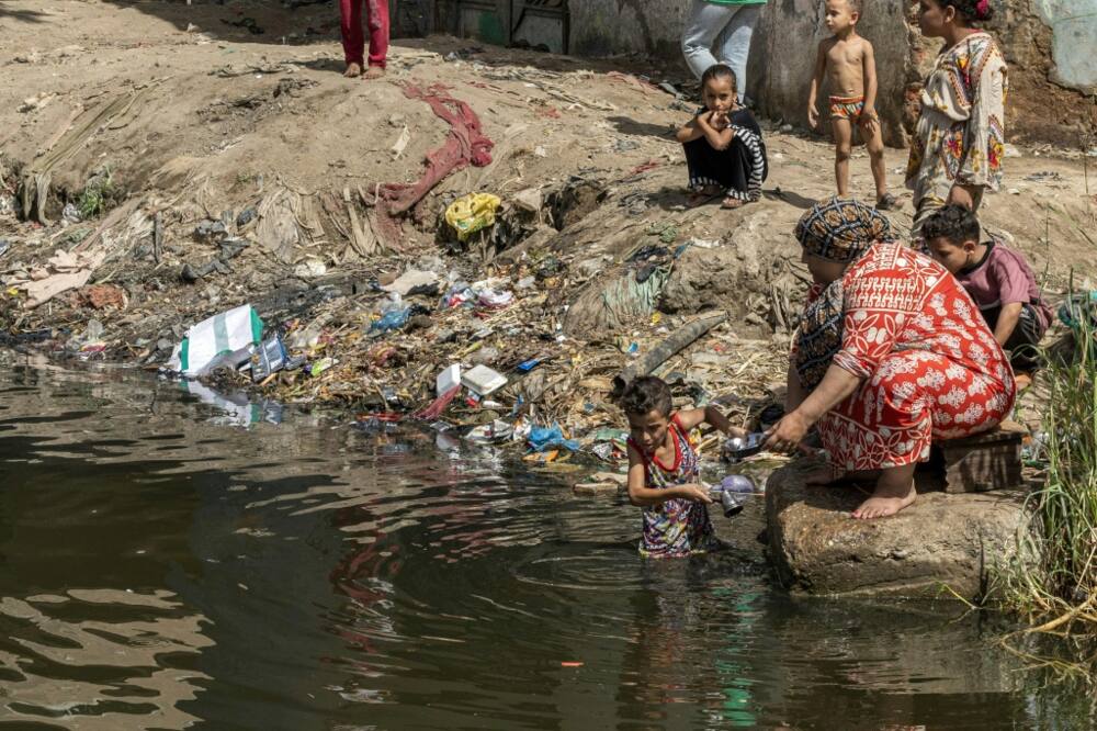 A child helps a woman wash pots in the Nile near Giza in Egypt