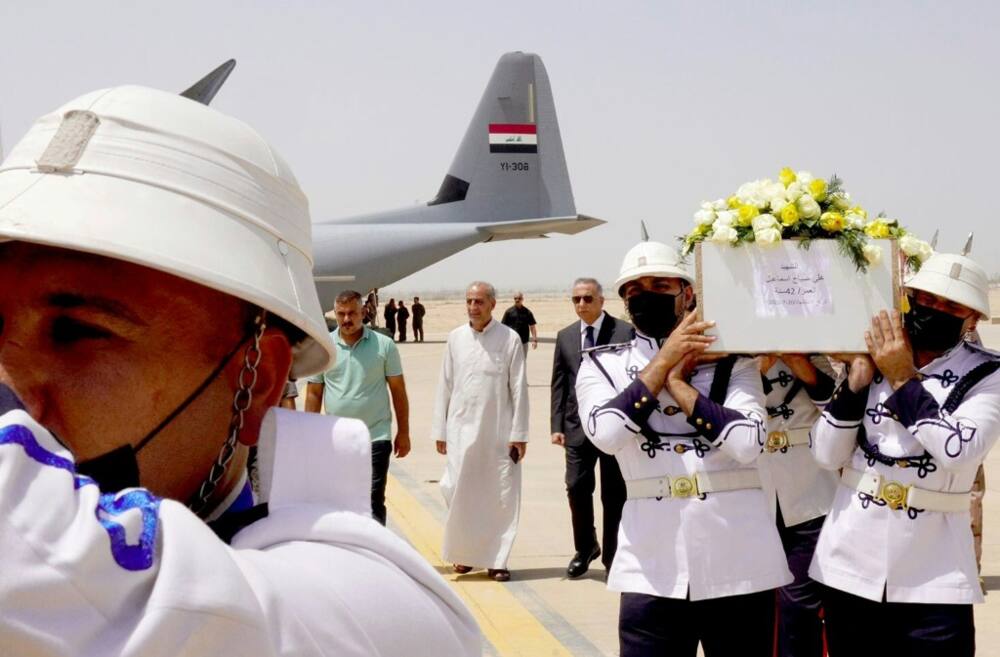 Honour guards at Baghdad airport carry caskets of the victims