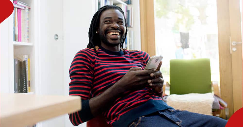 A man holding a phone laughing.