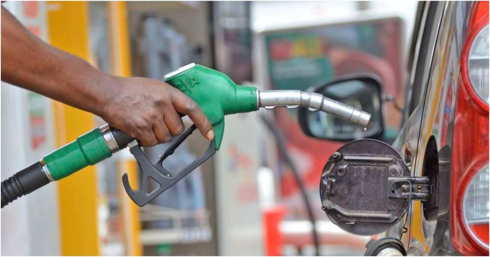 A petrol attendant holding oil nozzle to pump to the car tank.