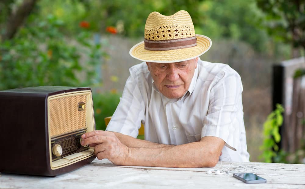 A senior man listening to the radio.