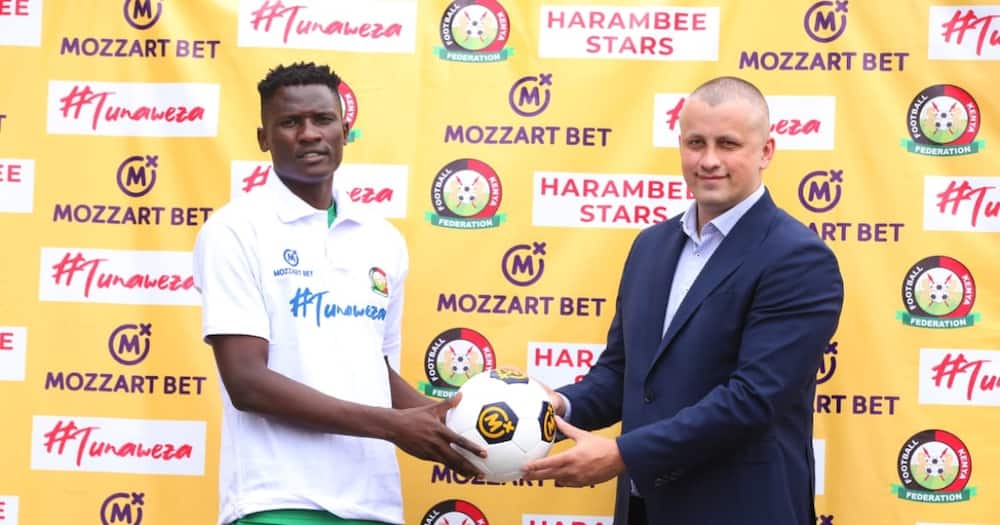 Harambee Stars player Michael Olunga (r) and a Mozzart Bet official. Photo: Mozzart Bet.
