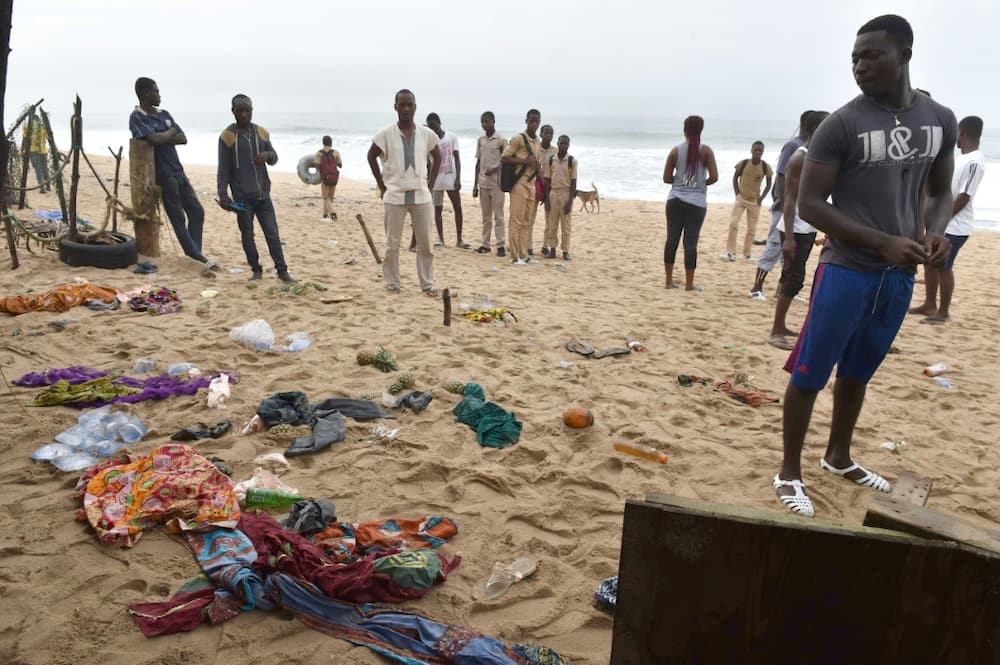 People look at clothes left on the beach following the attack
