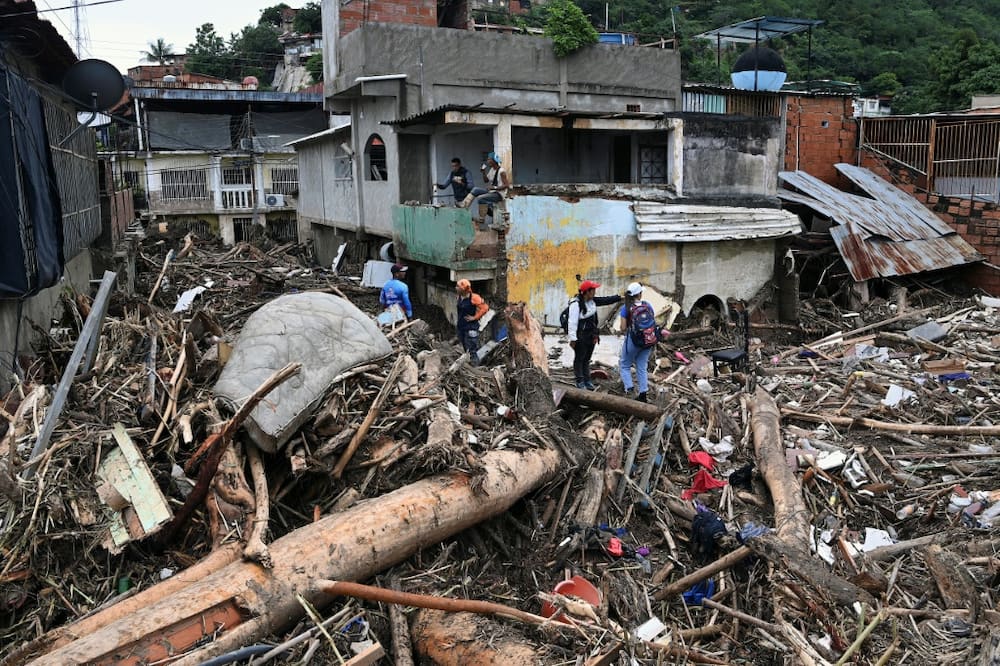 Rescuers and residents search through the rubble of destroyed houses for victims or survivors of a landslide during heavy rains in Las Tejerias, Venezuela, on October 9, 2022