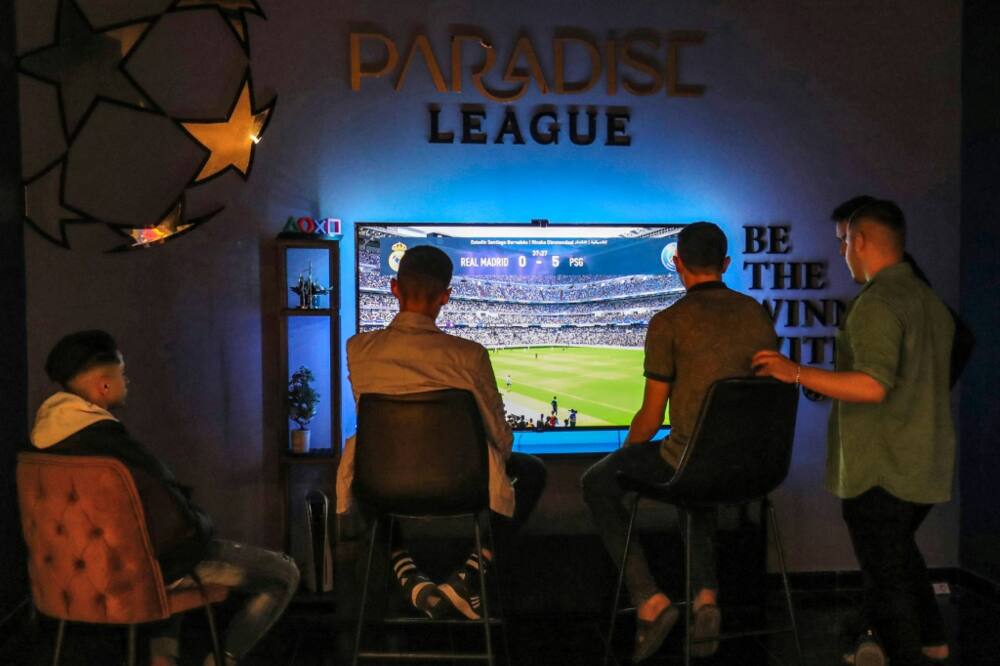 Young Libyans play and watch an electronic football game