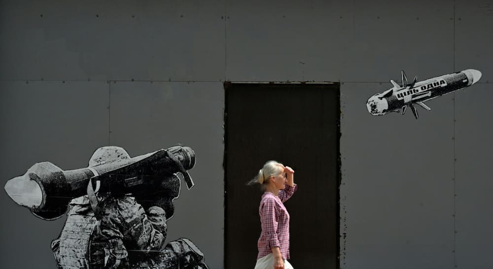A woman walks past a mural in Kyiv depicting a Ukrainian serviceman firing a US-made Javelin anti-tank missile in July 2022