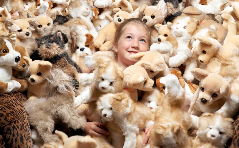 A girl surrounded by stuffed toys