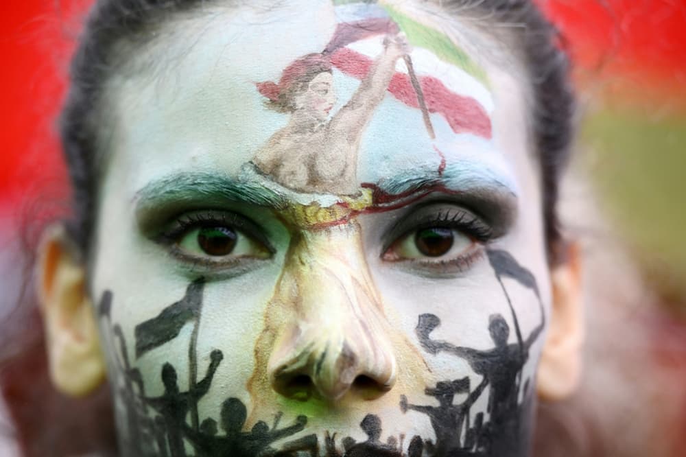 A woman wearing face-paint depicting France's iconic "Marianne" leading an uprising demonstrates in Paris against Iran's bloody crackdown on women-led protests against the country's strict dress code