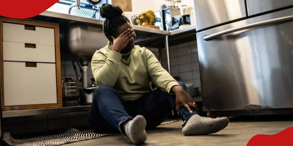 Photo of a distressed woman sitting in the kitchen floor.
