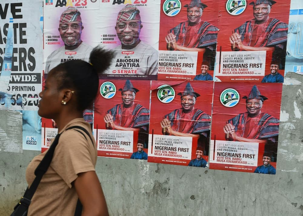 A woman walks past campaign posters of presidential aspirant of New Nigeria Peoples's Party (NNPP) Rabiu Kwankwaso.