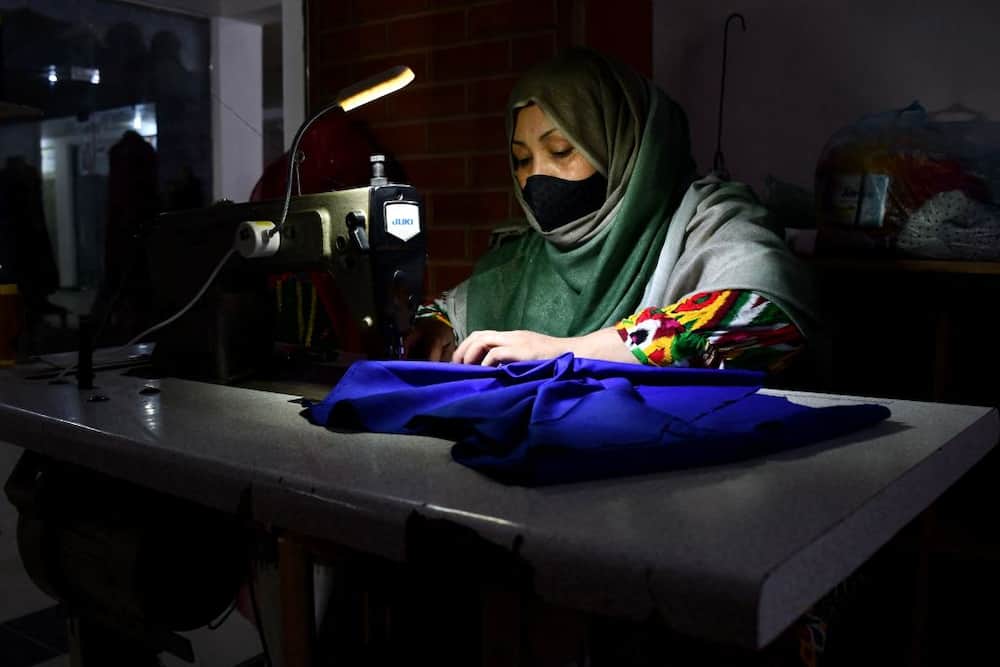 An Afghan woman tailor works inside a shop ahead of Muslim festival of Eid al-Adha, at a market in Mazar-i-Sharif