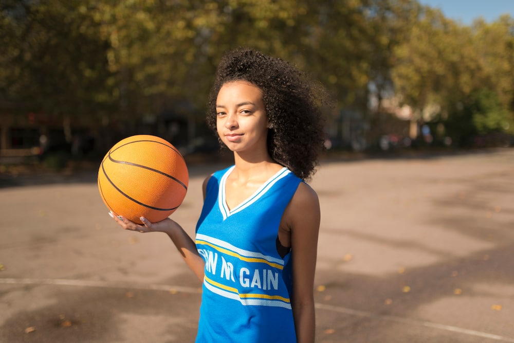 Portrait young female basketball player holding up basketball