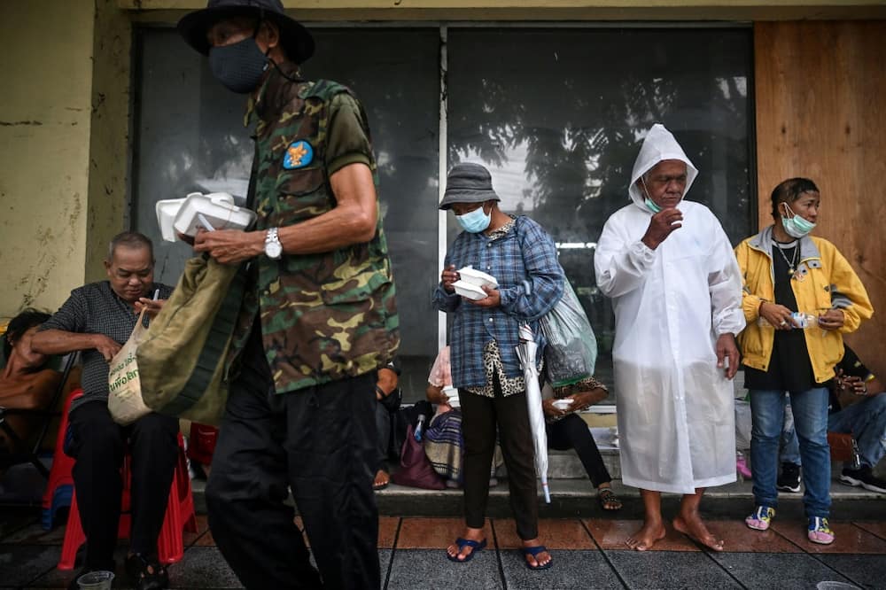 Unemployed Thais queue alongside homeless people waiting for free meals in Bangkok