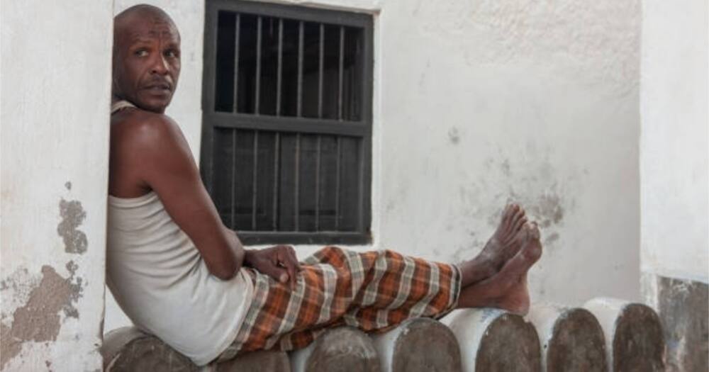 A Lamu man rests on the wall of a house.