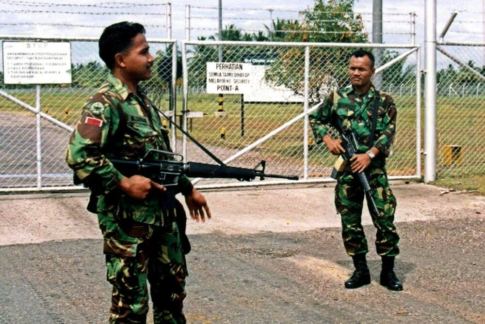Two Indonesian soldiers guard the gates of oil company ExxonMobil Indonesia's (EMOI) complex in Lhokseumawe, Indonesia, March 10, 2001