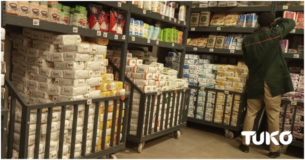 A supermarket attendant arranging unga on the shelf.