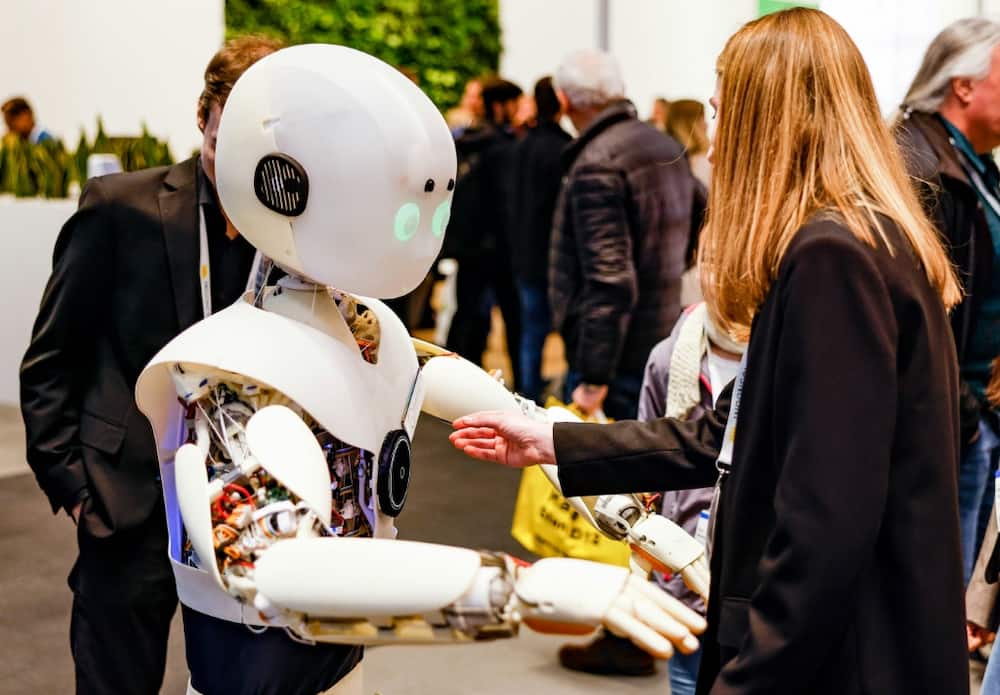 A woman interacts with a robot at a major trade fair in Hanover