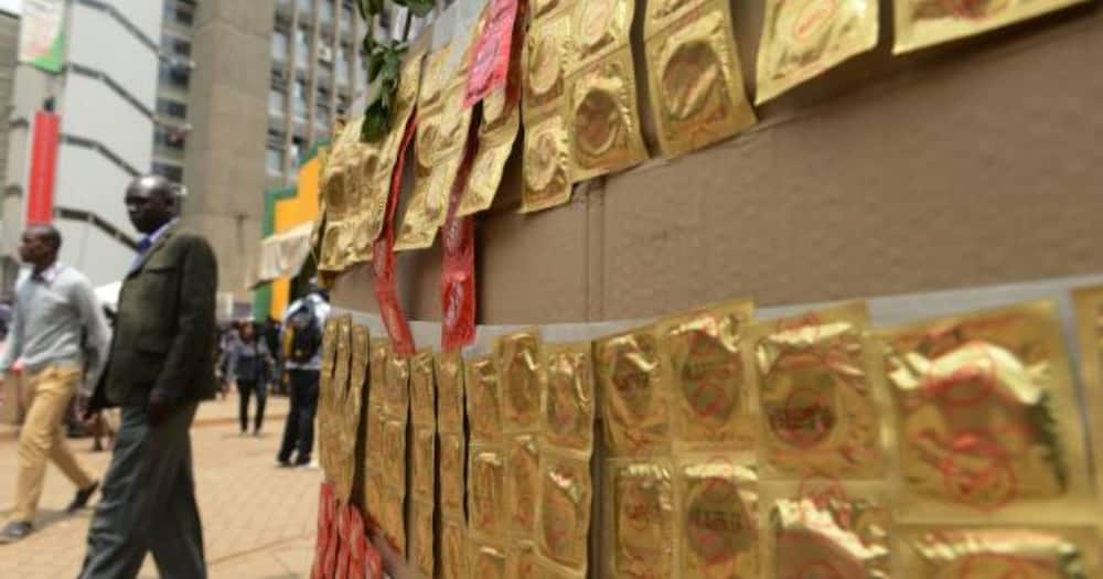 Kenyans walk past condoms exhibited in the streets. Photo: Getty Images.