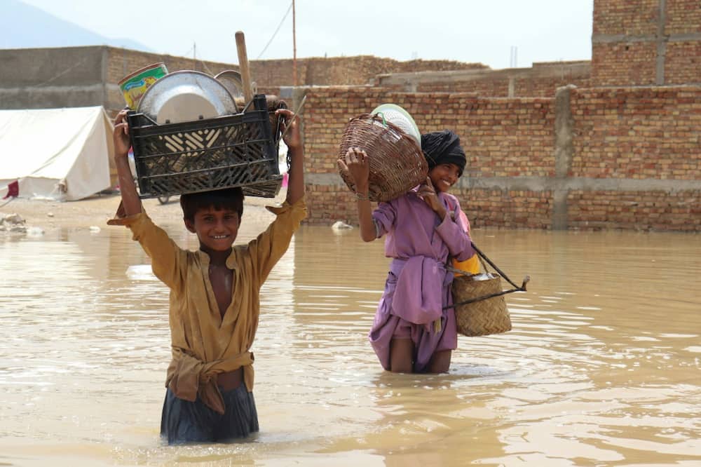 Children carrying household items through a flooded area near Quetta in Pakistan during the monsoon rains