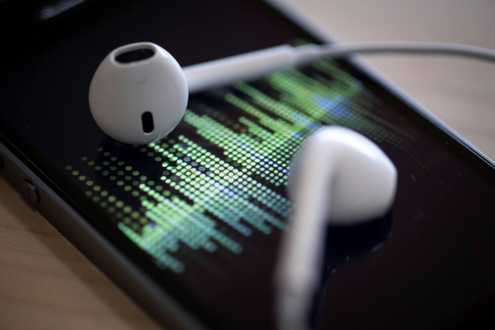 A picture taken on February 8, 2019 in Paris shows a smartphone and its earphones as an audio podcast is being played