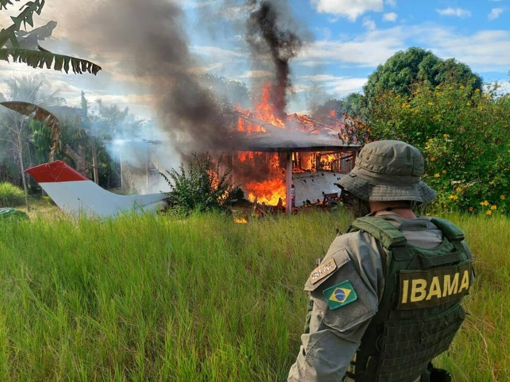 A handout picture released by the Brazilian Institute of Environment and Renewable Natural Resources shows an agent watching as an aircraft belonging to illegal miners burns during operations against deforestation in the Yanomami Indigenous territory