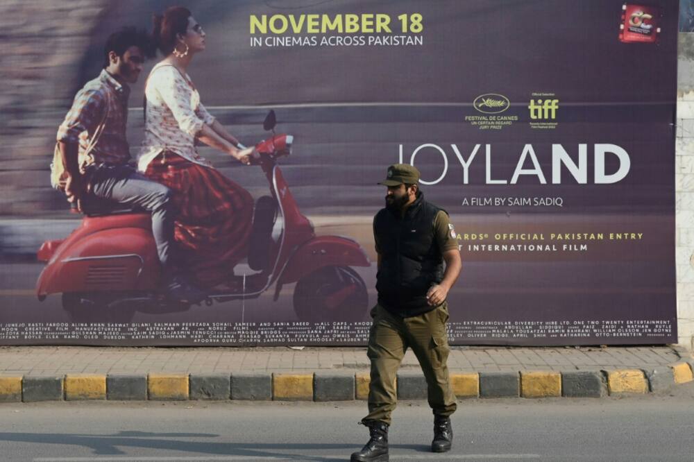 A policeman walks past a promotional banner of Pakistan-produced movie "Joyland" in Lahore on November 16, 2022