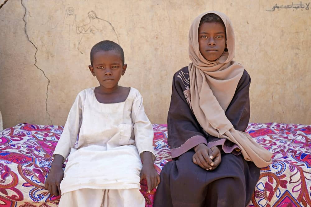 Zahra Hussein, aged nine, forced to stay home helping out with household chores as money grew ever tighter, poses with her brother in eastern Sudanese village of Ed Moussa