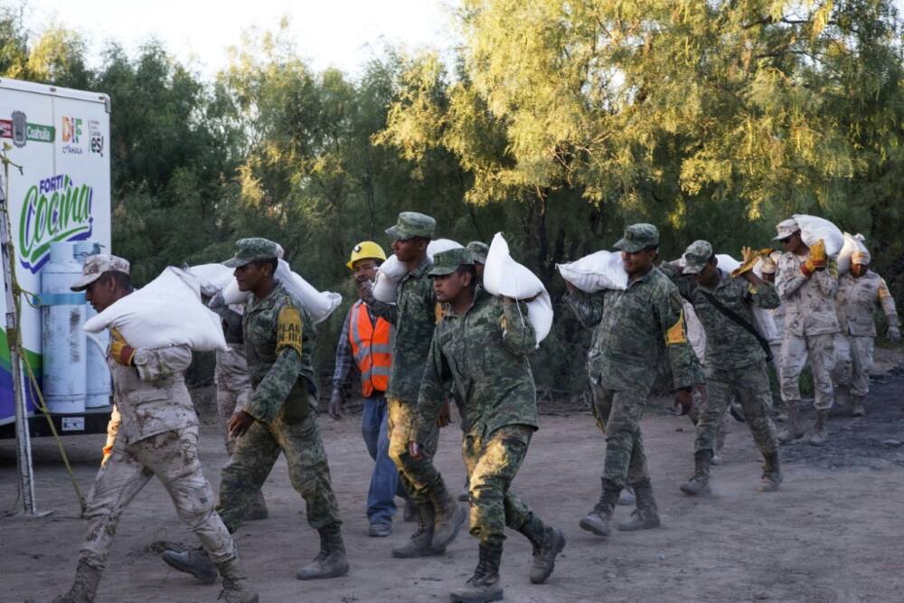 Mexican soldiers carry sand bags near the coal mine where rescuers are battling to save 10 workers trapped for nearly a week