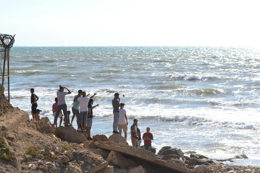 Lebanese men look towards the sea near the Arida border crossing with Syria