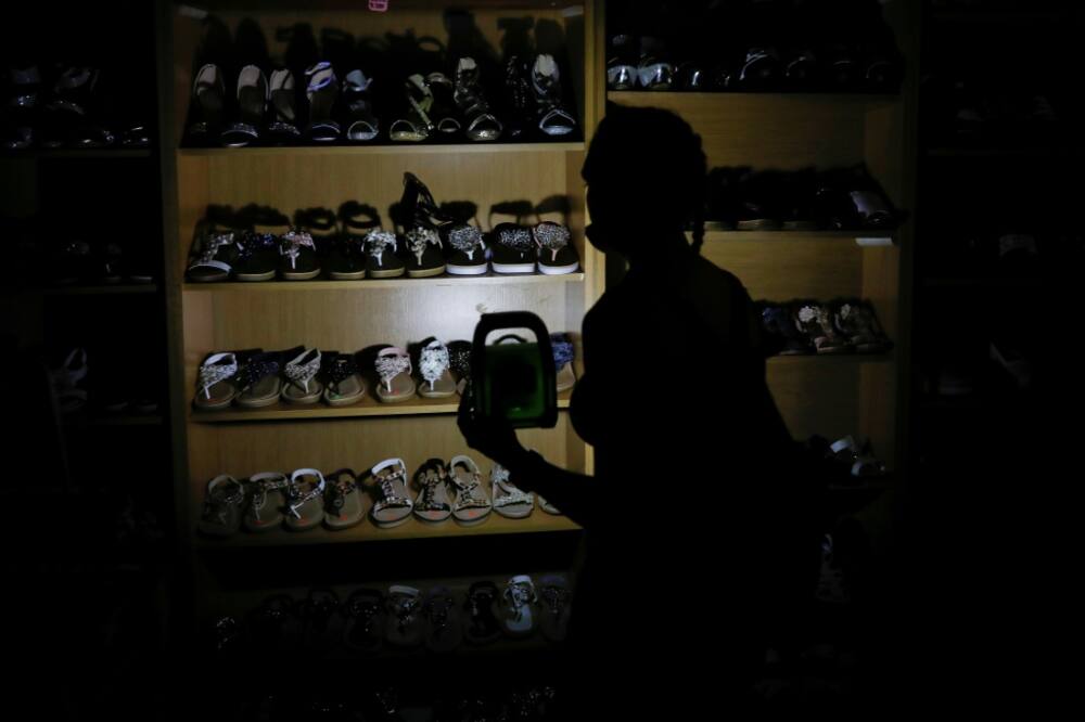Go with the glow: A shopper uses a rechargeable LED lamp to illuminate a shoe rack