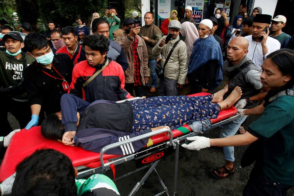 People evacuate a wounded woman on a stretcher following a landslide triggered by earthquake in Cianjur