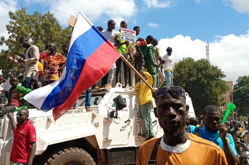 Pro-Moscow: Demonstrators waving a Russian flag stand atop a UN peacekeepers' vehicle in Ouagadougou on Sunday