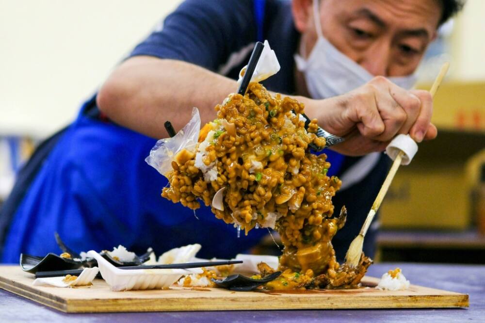 A worker applies the finishing touches on his plastic cyclone of fermented soybeans, aka the 'nattornado'