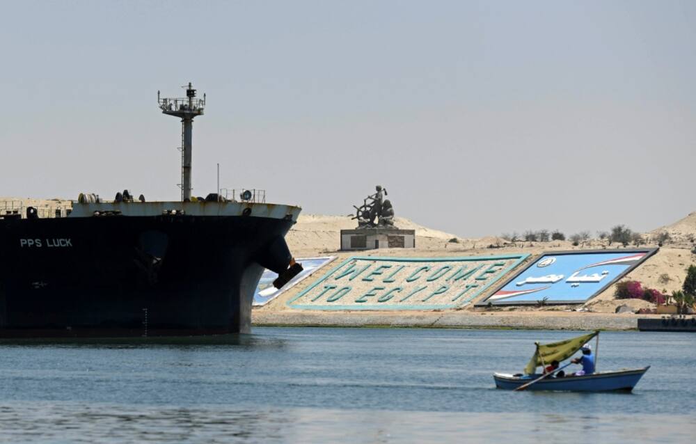 A file photo taken on May 27, 2021 shows a small boat sailing in front of a ship in Egypt's Suez Canal