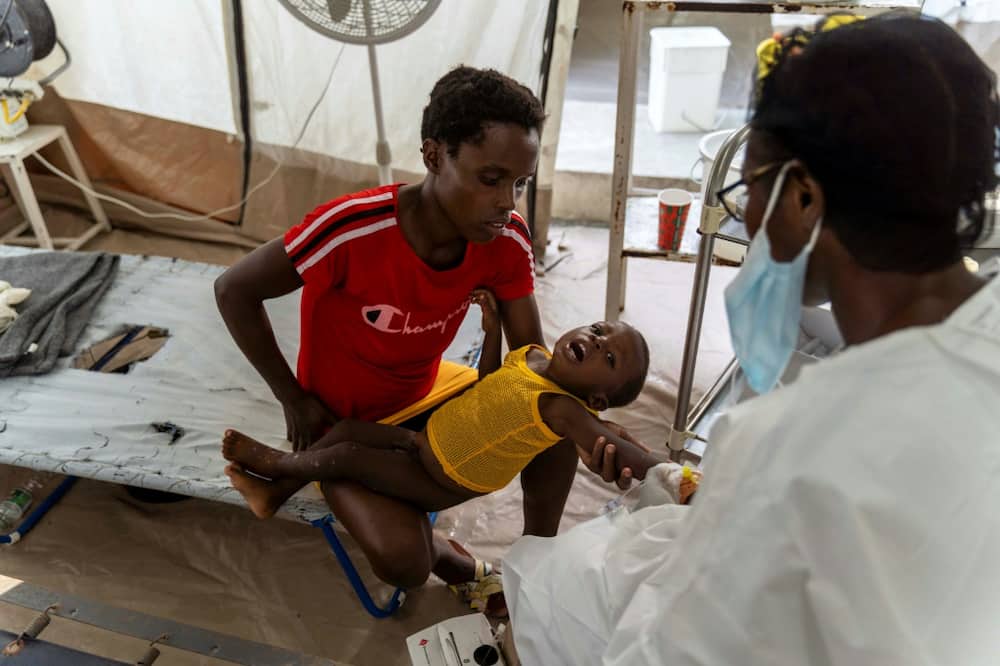 A woman holds a child showing symptoms of cholera at a clinic run by Doctors Without Borders in Cite Soleil, a densely populated area of Port-au-Prince, Haiti, in October 2022