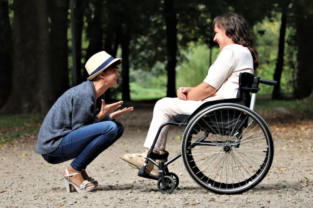 A girl and a disabled woman chatting happily.