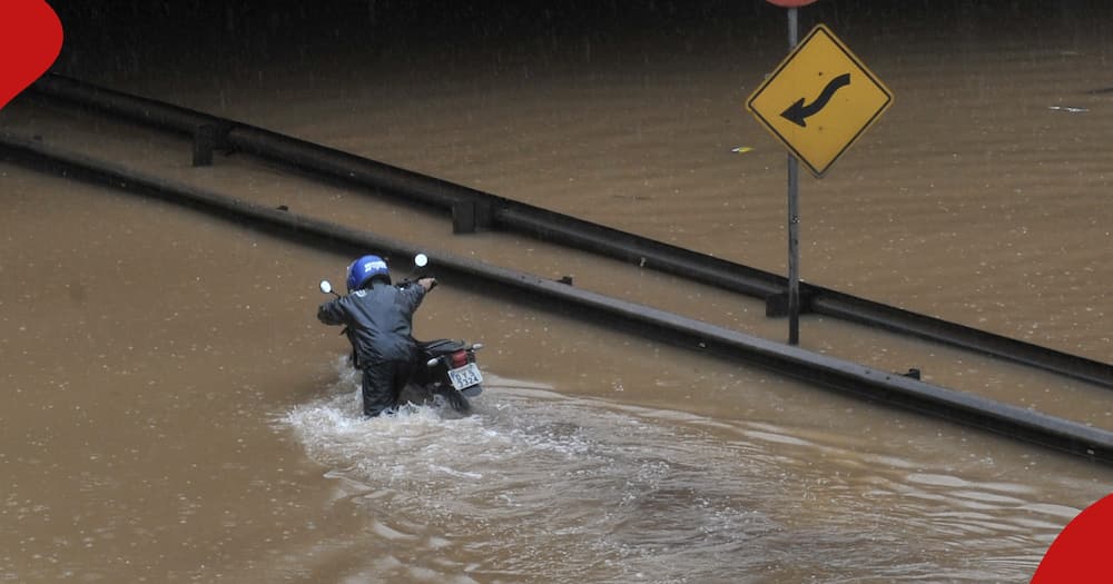 Boda boda rider struggling on a submerged road.