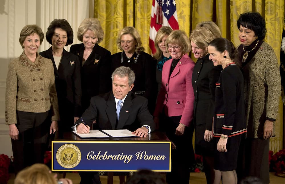 US President George W. Bush (C) signs a proclamation honoring Women's History Month during a ceremony in the East Room of the White House in Washington, DC.